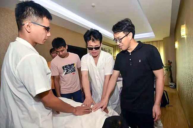 王永澄（右二）正在指導盲人學員按摩技法