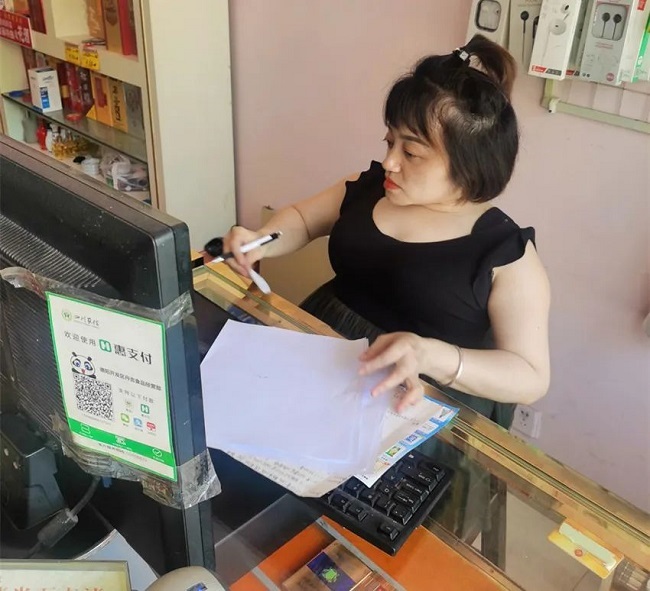 圖為廖丹在店鋪里查看賬目
