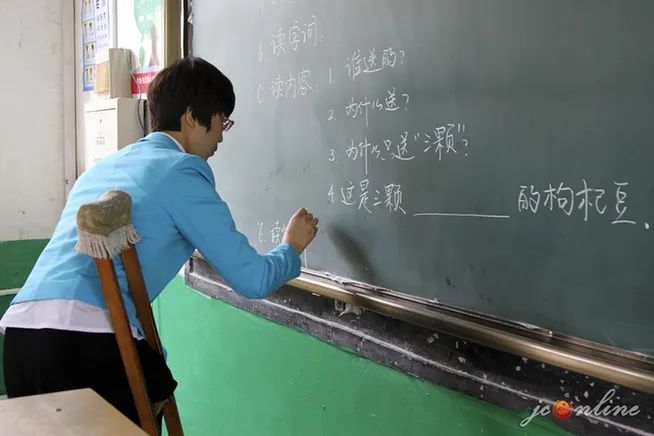 圖為王平用拄拐的右手進行板書