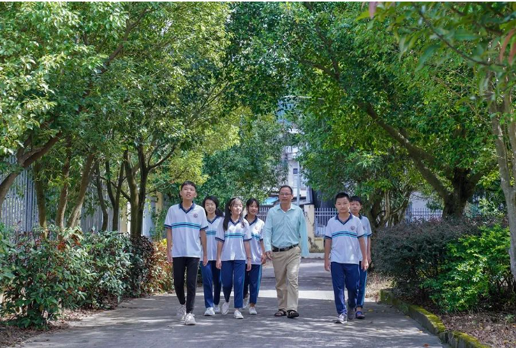 圖為梁木山和他的學(xué)生在校園里漫步