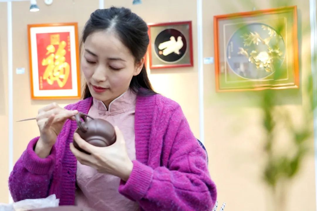 圖為袁露露在展覽現(xiàn)場(chǎng)為觀眾表演了紫砂貼花的技藝