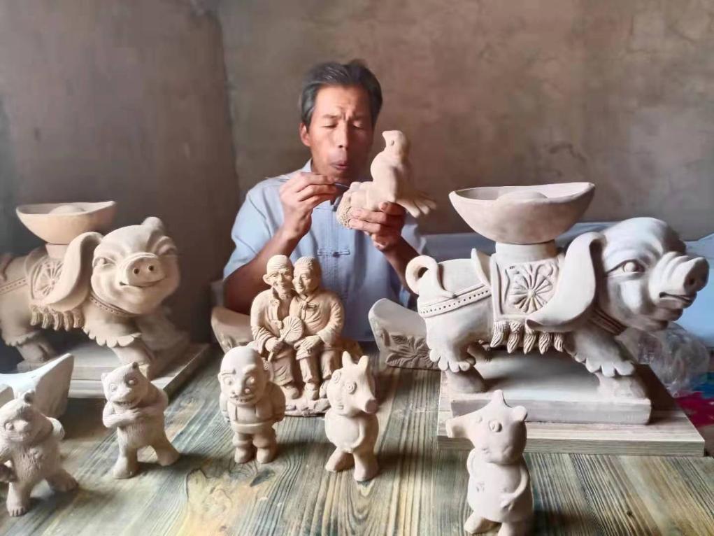 圖為劉泉在雕刻泥塑制品