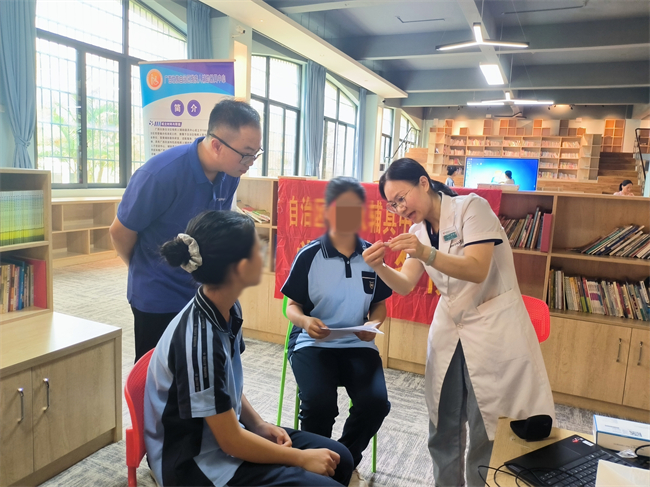 圖為技術人員為殘疾學生講解助聽器的使用方法