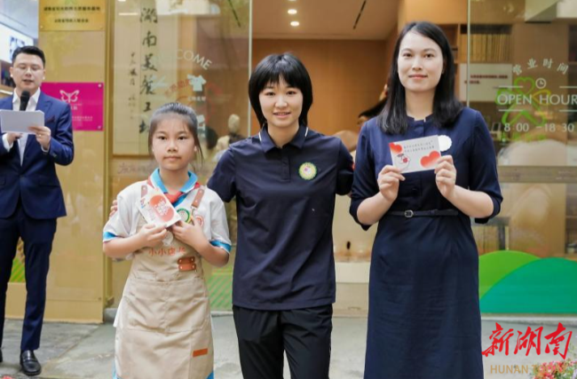 圖為文曉燕為志愿者頒發(fā)一日店長與小小店長徽章